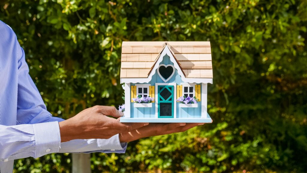 Professionista immobiliare che tiene una casa delle bambole, a simboleggiare quanto sia facile acquistare e vendere case con i-buyers